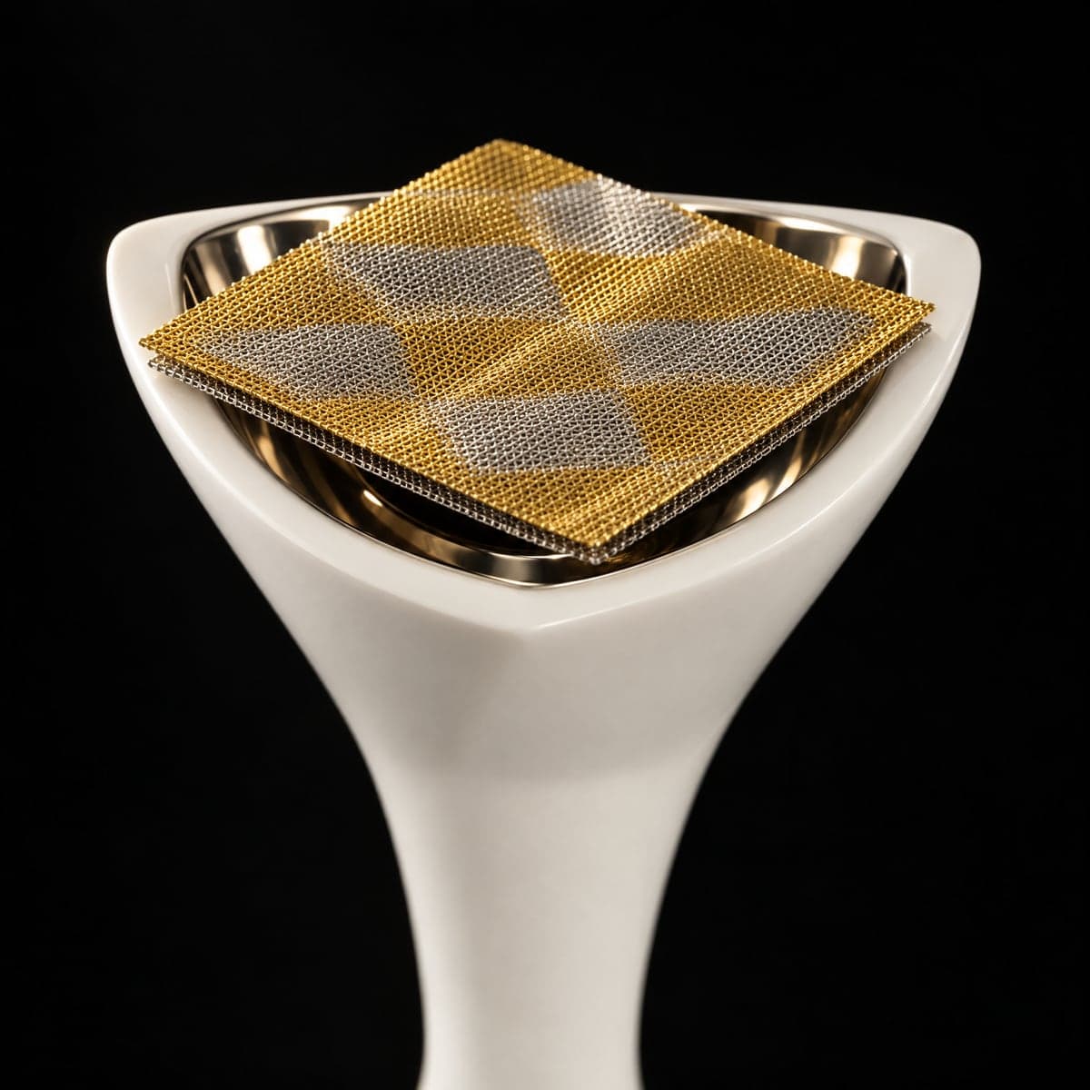 The double-layered mesh, gold and silver in a quilted pattern, resting on the burner