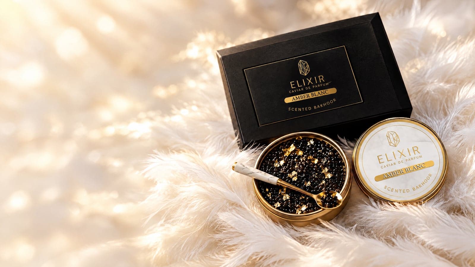 Amber Blanc: the open tin of pearls with gold leaf, a marble-handled gold spoon, the ivory tin and its box, on white feathers