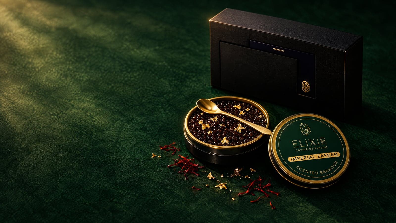 Imperial Zafran: the open tin of pearls with gold leaf, a gold spoon, the green tin and its box, on emerald green with threads of saffron