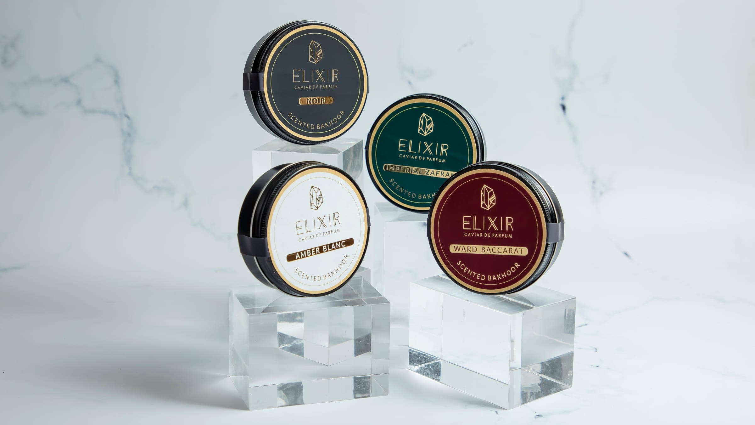 The four Caviar Bakhoor tins, Noir, Ward Baccarat, Imperial Zafran and Amber Blanc, arranged on marble