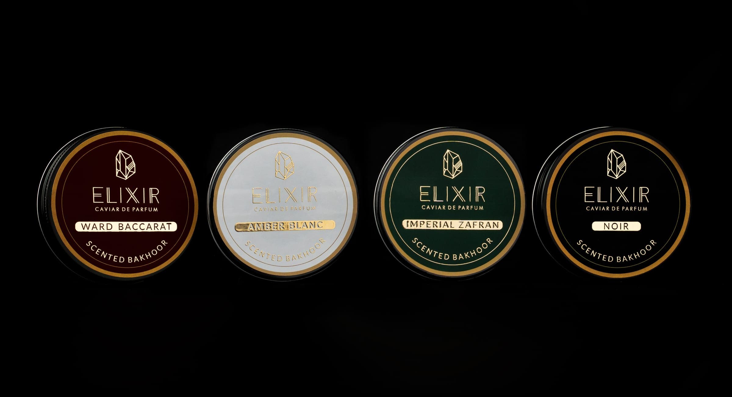 The four tins, Ward Baccarat, Amber Blanc, Imperial Zafran and Noir, lit against black