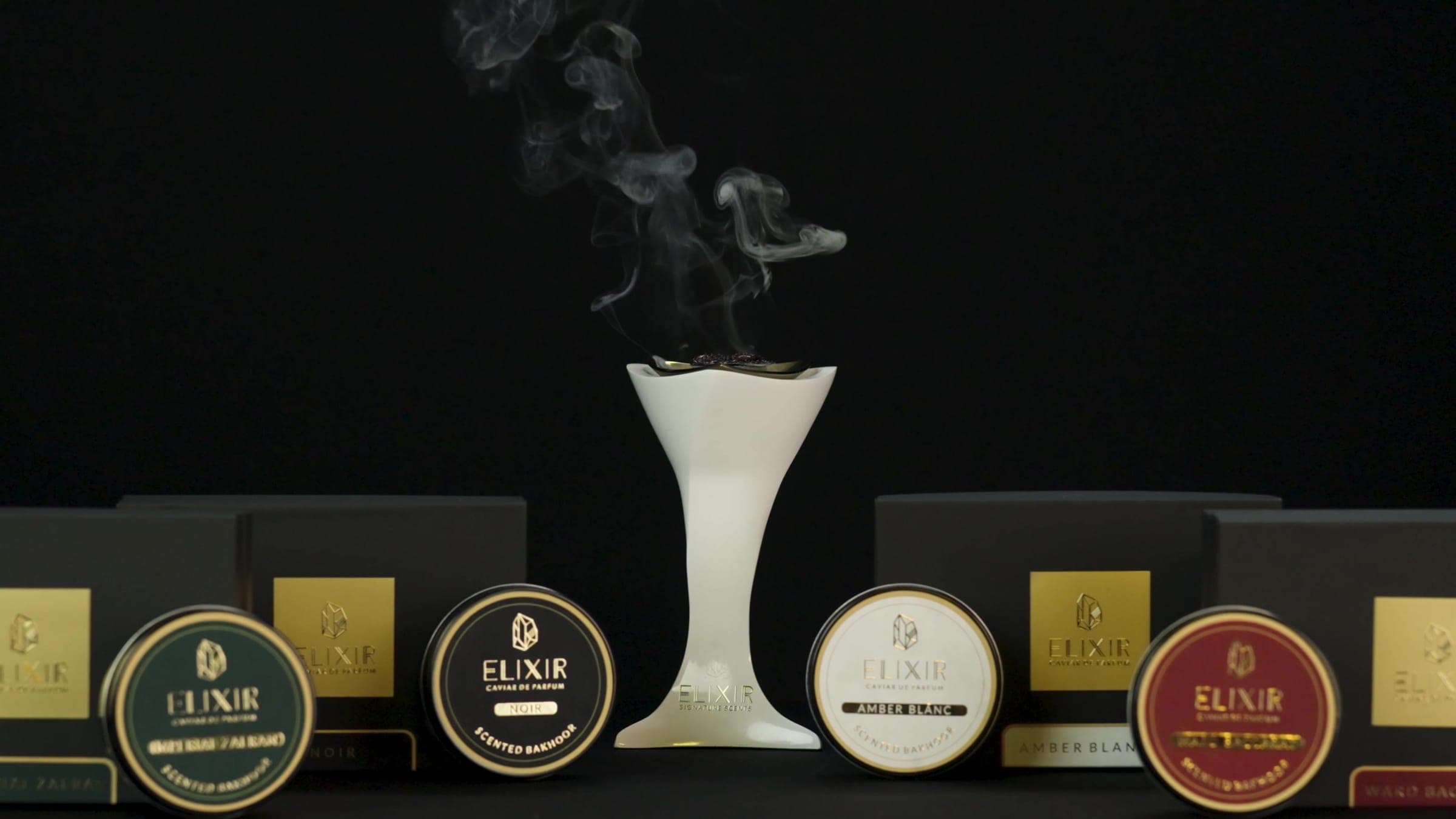 The white burner with smoke rising from it, the four Caviar Bakhoor tins and boxes around it