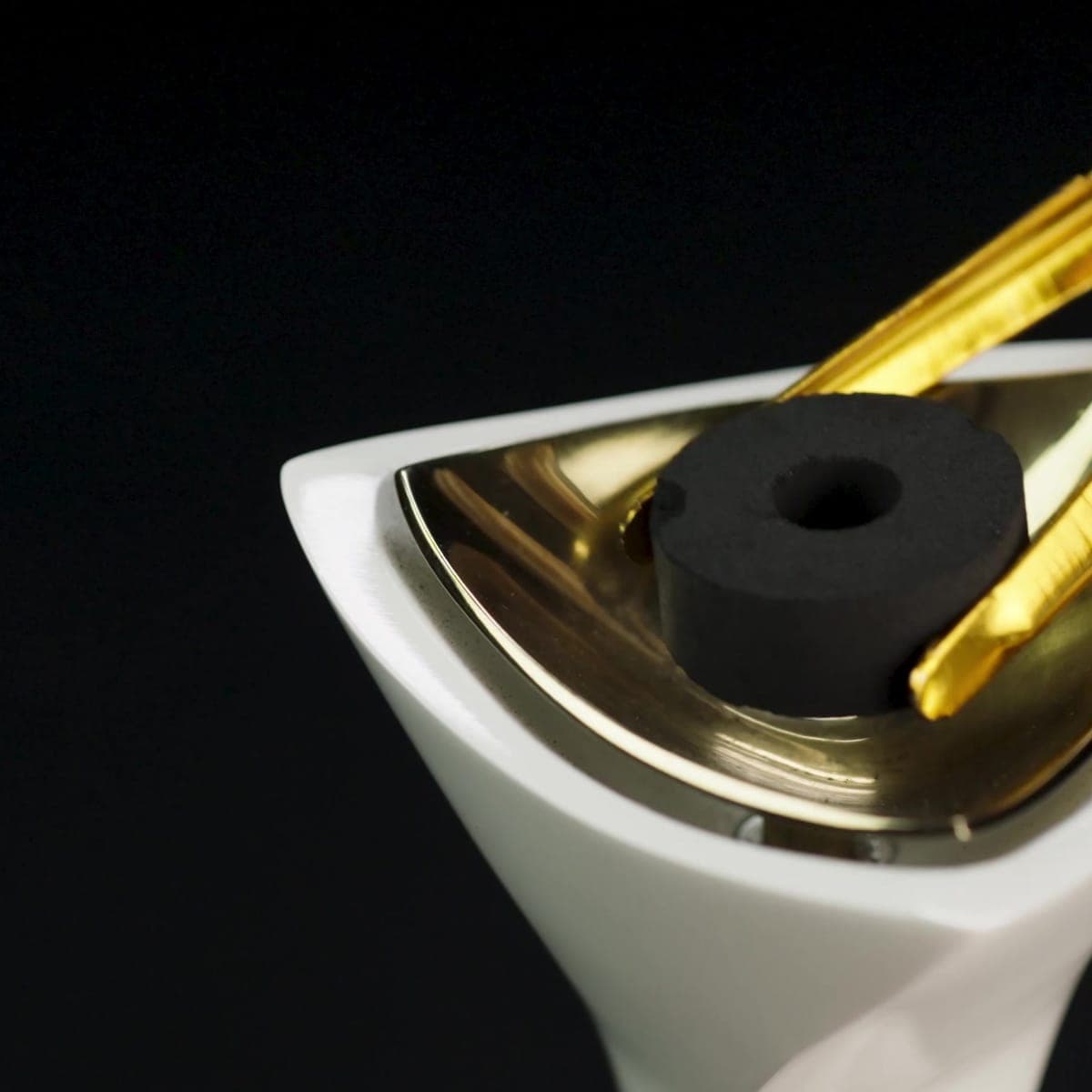 Gold tongs setting the charcoal block in the burner